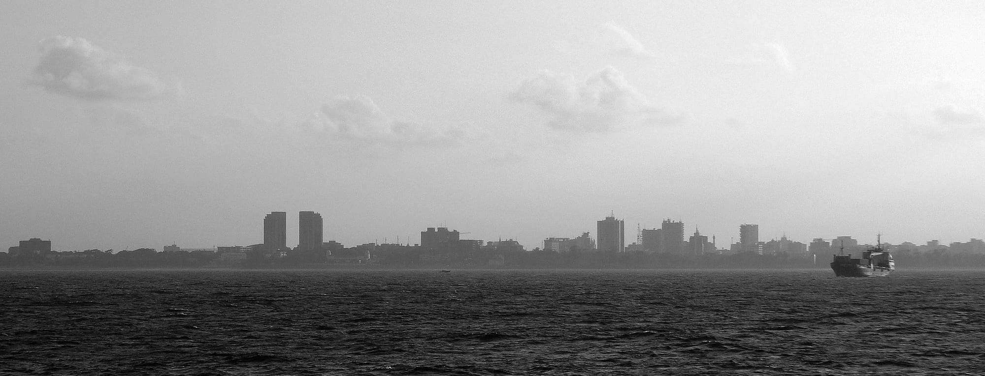 The Dar es Salaam skyline seen across the water under a grey sky